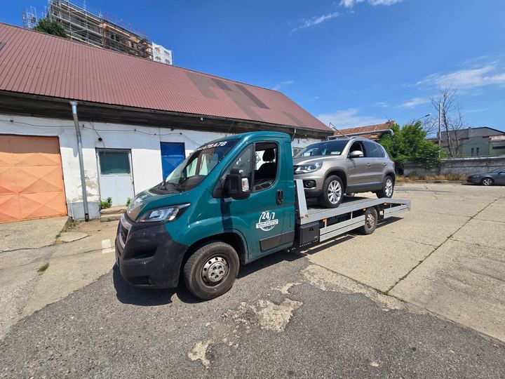 Transport auto la service: SUV gri pe autoplatformă în curtea unui service